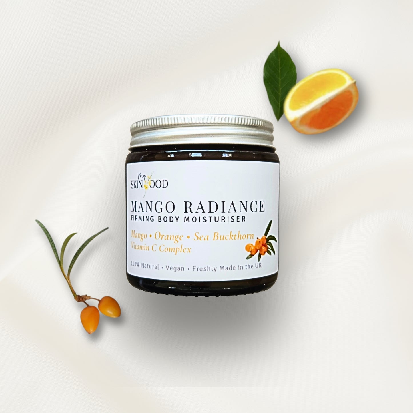 Jar of My Skinfood Mango Radiance firming body moisturizer with mango sea buckthorn and orange slices on a light background